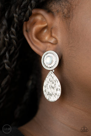 Paparazzi Jewelry. Necklace, Bracelet, Earrings, Rings A hammered silver teardrop dangles from the bottom of an ornate silver disc that is dotted with a dreamy opal beaded center. Earring attaches to a standard clip-on fitting.  Sold as one pair of clip-on earrings.  New Kit Clip On Earring